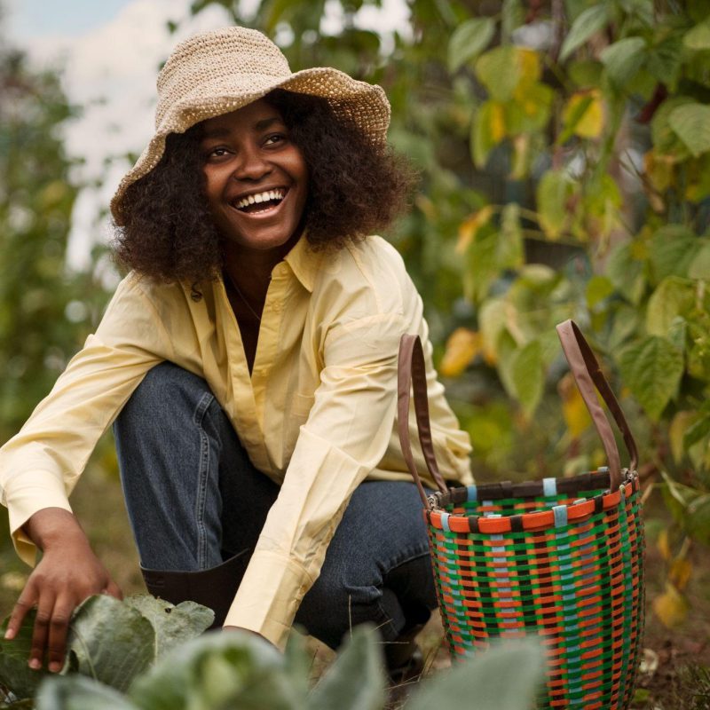 Une productrice accroupie dans son potager, panier à la main