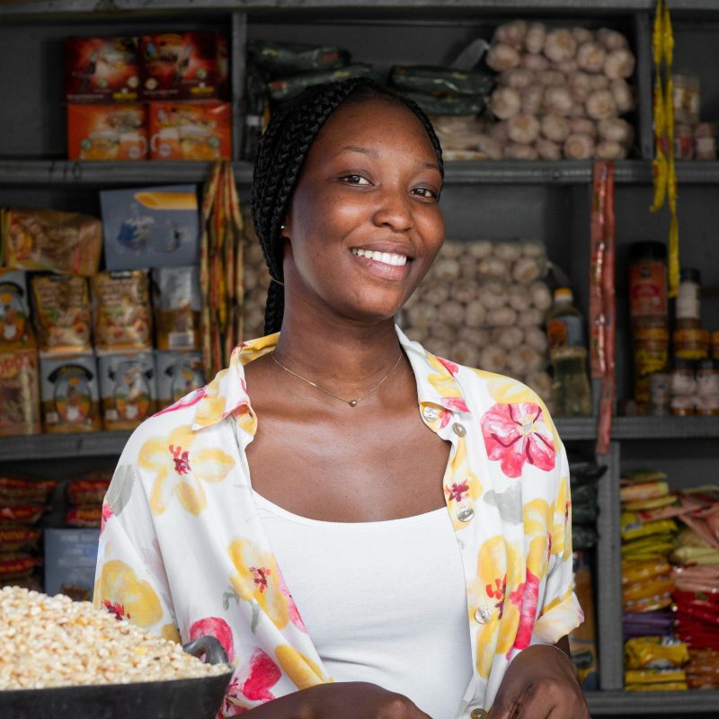 Une commerçante souriante derrière son comptoir de céréales et de légumineuses