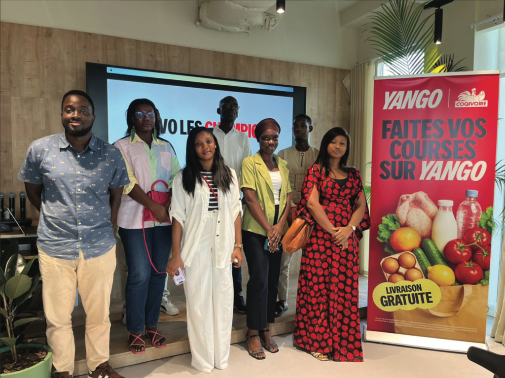 Un groupe de participants pose devant un stand Yango
